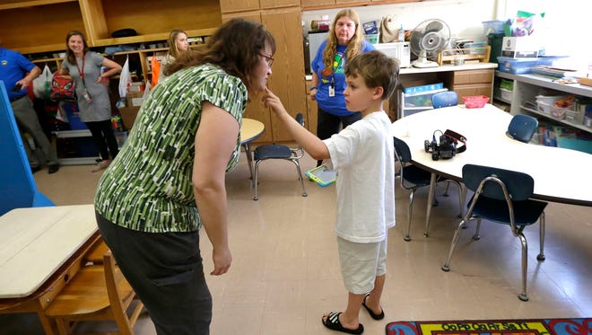 Logan Lucas, an eight-year-old 2nd grader at  Shady Lane Elementary School student touches chin of his mother, Nicole Lucas, as he communicates with her in his classroom.