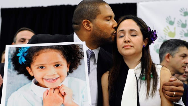 Jimmy Greene, left, kisses his wife Nelba Marquez-Greene as he holds a portrait of their daughter, Sandy Hook School shooting victim Ana  Marquez-Greene at a news conference at Edmond Town Hall in Newtown, Conn., Monday, Jan. 14, 2013.