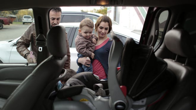Waseem Ilotte, left, and his wife, Lara Al Aso, load their son Aras Ilotte, 18 months old, into their vehicle after receiving aid at the Chaldean American Ladies of Charity Center in Troy, Mich., on Oct. 10, 2014.