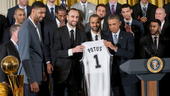 President Barack Obama accepts a San Antonio Spurs jersey from team members Tim Duncan, Manu Ginobili and Tony Parker.