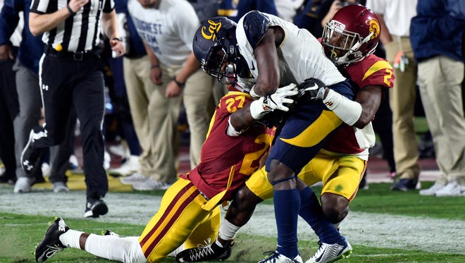 USC defensive backs Adoree' Jackson, right, and Ajene Harris tackle Cal wide receiver Melquise Stovall at Los Angeles Memorial Coliseum.