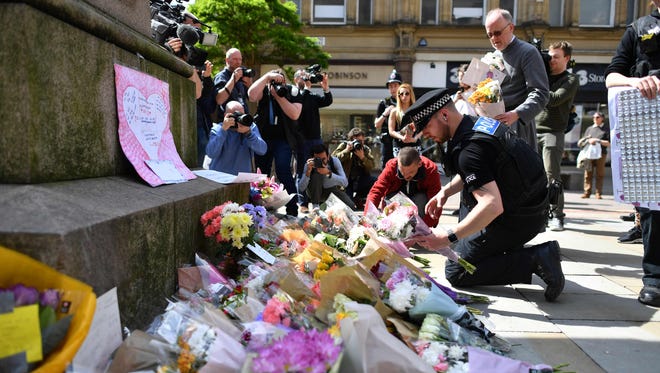 Police officers relocate tributes in St Ann's Square in Manchester, England May 23, 2017, that were laid as a mark of respect to those in killed and injured in a deadly terror attack at the concert the night before.