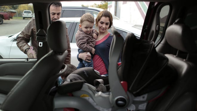 Waseem Ilotte, left, and his wife, Lara Al Aso, load their son Aras Ilotte, 18 months old, all from Warren, into their vehicle after receiving aid at the Chaldean American Ladies of Charity Center in Troy on Oct. 10, 2014.