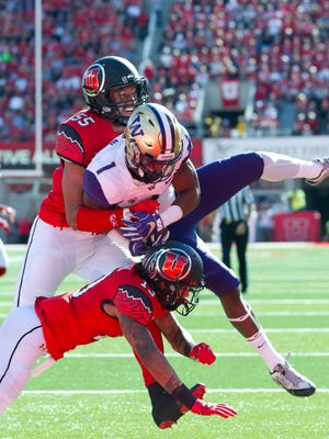 Washington Huskies wide receiver John Ross (1) scores a touchdown as he is tackled by Utah Utes defensive back Jordan Fogal (13) and linebacker Kavika Luafatasaga (55) during the first half at Rice-Eccles Stadium.