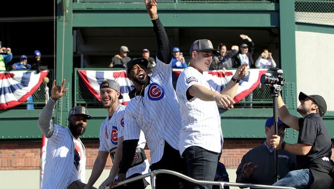 Cubs players wave to fans outside Wrigley.