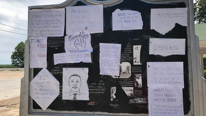 A group called Cultural Leadership places hand written notes on the Emmett Till marker.