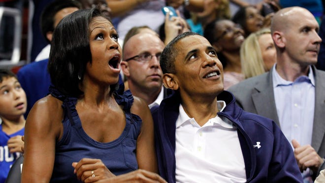 President Barack Obama and first lady Michelle Obama look up at themselves on the large in-house video screen for the "Kiss Cam"while watching the first half of Team USA and Brazil in an Olympic men's exhibition basketball game Monday, July 16, 2012, in Washington.
