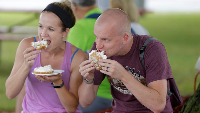 Brittany Smith (left) and her husband John Smith, both from Madison, enjoy a cream puff.