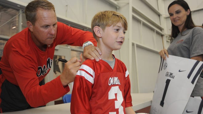 Mississippi head coach Hugh Freeze, left, autographs the jersey of fan Forrest Rowe at Meet The Rebels at the University of Mississippi's Indoor Practice Facility in Oxford, Miss. on Saturday, August 17, 2013. Fans were able to get autographs from the university's football, soccer, volleyball, rifle and spirit squads.
