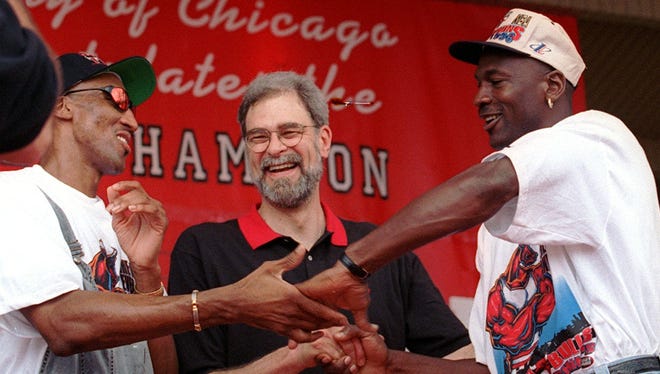 1996: Scottie Pippen, Jackson, and Michael Jordan share a three-way victory handshake during the NBA Championship celebration.