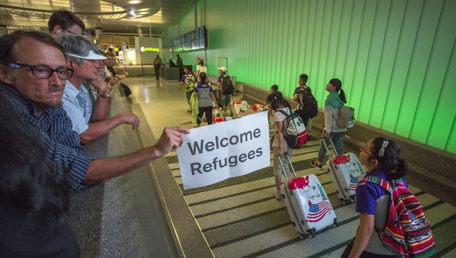 John Wider carries a welcome sign near arriving international travelers on the first day of the the partial reinstatement of the Trump travel ban, temporarily barring travelers from six Muslim-majority nations from entering the U.S., at Los Angeles International Airport (LAX).