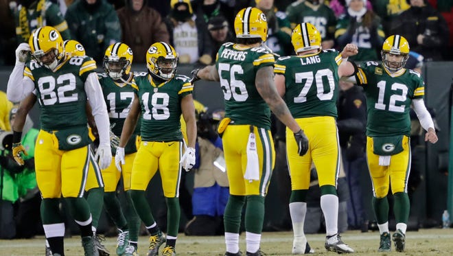 Green Bay Packers quarterback Aaron Rodgers (12) celebrates with teammates after throwing a touchdown pass against the New York Giants in the second quarter in the NFC Wild Card playoff football game at Lambeau Field.