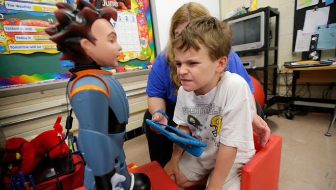 Logan Lucas, an eight-year-old 2nd grader at  Shady Lane Elementary School in Menomonee Falls, mimics the face made by robot Milo as special education teacher Karen Richie observes.