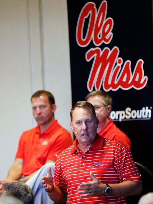 In this July 18, 2017 photo, Mississippi athletic director Ross Bjork, left, and Mississippi Chancellor Jeffrey Vitter, partially obscured, listen as football coach Hugh Freeze speaks before alumni and athletic supporters during a Rebel Road Trip visit in Jackson, Miss. Mississippi announced Thursday that Freeze had resigned after five seasons, bringing a stunning end to a once-promising tenure. Offensive line coach Matt Luke has been named the interim coach.