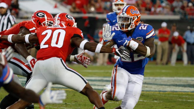 Florida running back Lamical Perine (22) runs with the ball as Georgia safety Quincy Mauger (20) attempts the tackle.