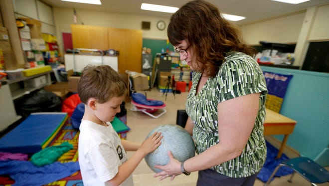 Logan Lucas, an eight-year-old 2nd grader at  Shady Lane Elementary School student shows his mother, Nicole Lucas, a globe in his classroom.