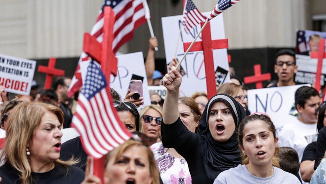 Dhona Alhaddad, of Dearborn, Mich., center right, protest the arrest of more than 100 Iraqi nationals by Immigration and Customs Enforcement outside of the Theodore Levin United States courthouse in Detroit on Wednesday, June 21, 2017.
