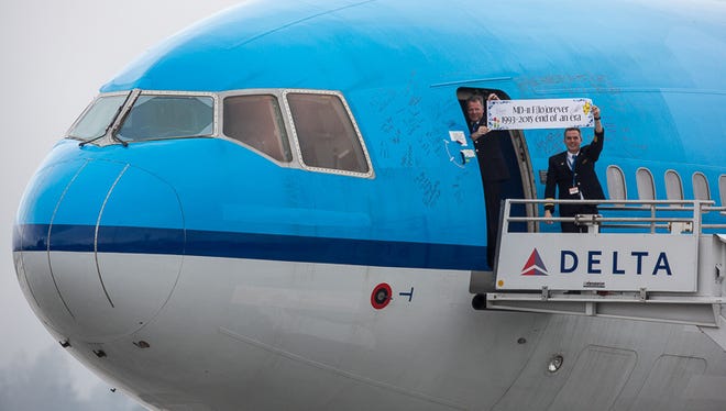 Pilots from on board the last MD-11 to fly regularly scheduled passenger flights hold up a sign greeting well-wishers and aviation enthusiasts during a stopover in Seattle on Jan. 11, 2015. The jet, formerly owned by KLM, was en route to a California aircraft 'graveyard.'