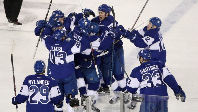 Maple Leafs center Auston Matthews (34) is congratulated by teammates after scoring the game-winning goal in overtime against the Red Wings during the Centennial Classic.