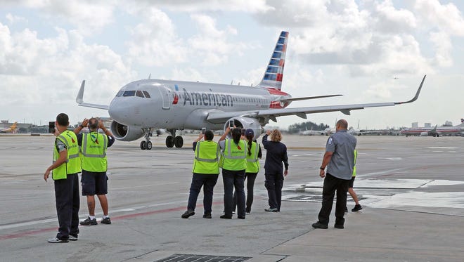 American Airlines ground employees witness the inaugural flight from the tarmac of Miami International as an American Airlines jetliner heads for Cienfuegos, Cuba on Sept. 7, 2016.