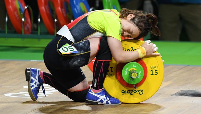 Hiromi Miyake (JPN) hugs the weights during the women's 48kg weightlifting event in the Rio 2016 Summer Olympic Games at Riocentro.
