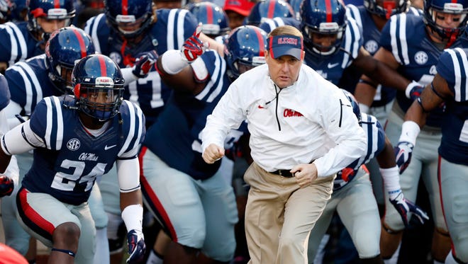 Mississippi football coach Hugh Freeze and his team runs onto the field prior to their game against Tennessee at an NCAA college football game in Oxford, Miss., Saturday, Oct. 18, 2014. (AP Photo/Rogelio V. Solis)