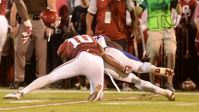 Oklahoma safety Steven Parker (10) loses his helmet while tackling Kansas running back Taylor Martin (24) during the second quarter.