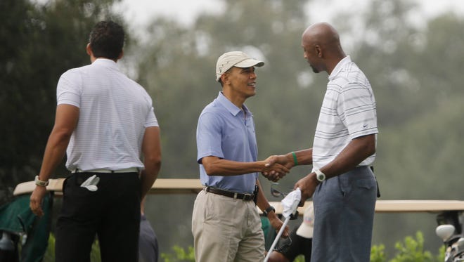 President Barack Obama shakes hands with former NBA player Alonzo Mourning at Grande Oaks golf club, Saturday, Nov. 9, 2013 in Ft. Lauderdale, Fla.