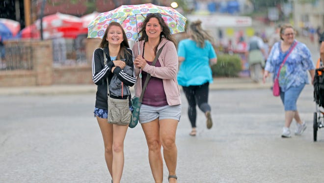 Lizzy Swiger (left) and her mother Stacey Swiger, both of Cudahy, take shelter under and umbrella as a rain shower briefly hit the fairgrounds.