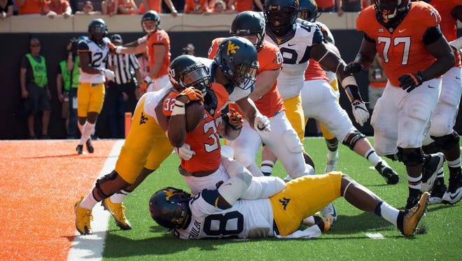 Oklahoma State Cowboys running back Chris Carson (32) stopped at the goal line by West Virginia Mountaineers defensive lineman Adam Shuler (88) and safety Kyzir White (8) during the second half at Boone Pickens Stadium. Cowboys won 37-20.
