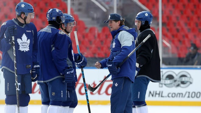Maple Leafs head coach Mike Babcock talks to centers Mitch Marner (16) and Tyler Bozak (42) and left wing James van Riemsdyk (25) as defenseman Jake Gardiner (51) looks on during practice for the Centennial Classic.