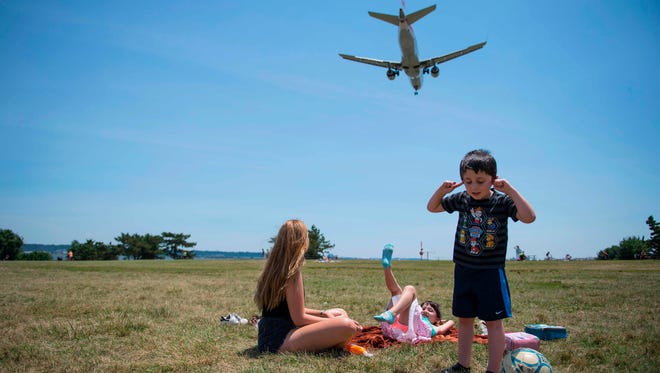 A young boy plugs his ears as his sister and nanny  watch from Gravelly Point Park as planes land at Reagan National Airport in Arlington, Virginia on June 29, 2017.
President Donald Trump's travel ban on people from six mostly Muslim countries comes into force late Thursday, as controversy swirls over who qualifies for an exemption based on family ties.
