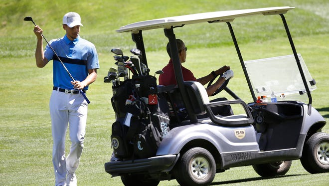 NBA basketball player Stephen Curry returns a club to the cart as President Barack Obama prepares to drive, Friday, Aug. 14, 2015, at Farm Neck Golf Club, in Oak Bluffs, Mass.