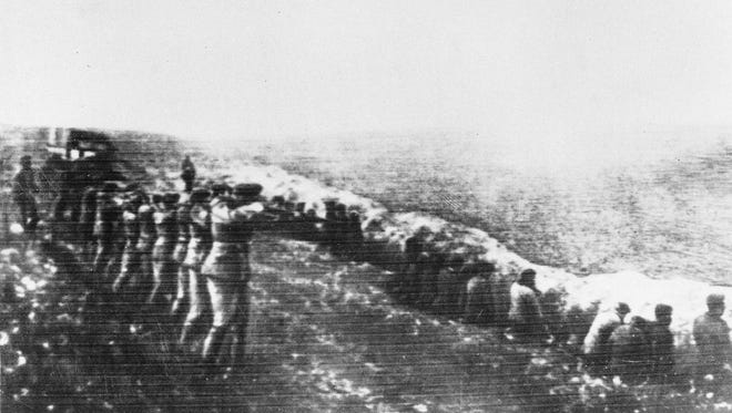 This 1942 file photo shows a Nazi firing squad shooting Soviet civilians in the back as they sit beside their own mass grave, in Babi Yar, Kiev.