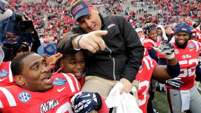 Mississippi head coach Hugh Freeze is hoisted by his players Jason Jones (38) and  Uriah Grant (93) at the end of the BBVA Compass Bowl NCAA college football game against Pittsburgh at Legion Field in Birmingham, Ala., Saturday, Jan. 5, 2013. Mississippi won 38-17. (AP Photo/Dave Martin)