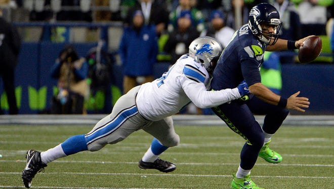 Seattle Seahawks quarterback Russell Wilson (3) is pressured by Detroit Lions defensive end Kerry Hyder (61) during the first half in the NFC Wild Card playoff football game at CenturyLink Field.