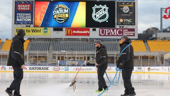 Workers spray the ice prior to the Pittsburgh Penguins hosting the Philadelphia Flyers in a Stadium Series hockey game at Heinz Field.