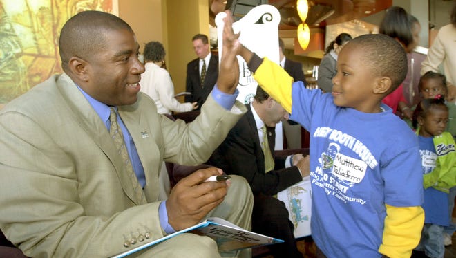 2000: Former NBA Star Earvin "Magic" Johnson, left, gets a high five from  Matthew Taliaferro following his reading, along with Starbucks Chairman Howard Schultz of "The Little Engine that Could" to a group of children from Literacy Chicago's Reach Out and Read program.