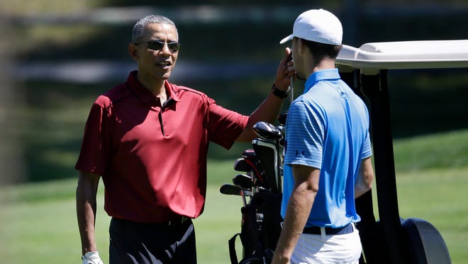 President Barack Obama speaks with Stephen Curry while golfing, Friday, Aug. 14, 2015, at Farm Neck Golf Club in Oak Bluffs, Mass.