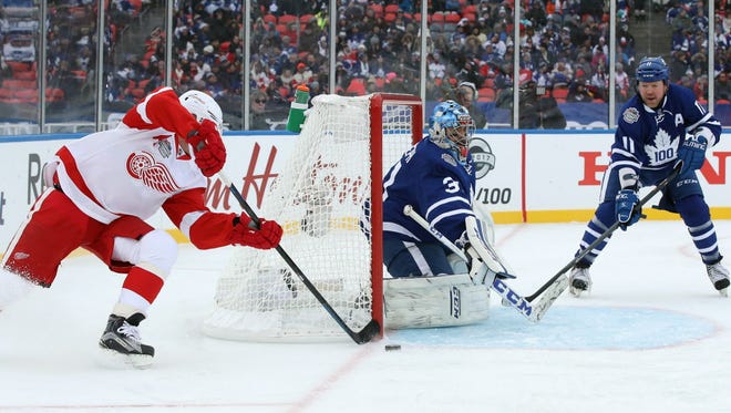 Maple Leafs goalie Curtis Joseph (31) stops a wrap-around attempt by Red Wings forward Kris Draper (33) during the Centennial Classic Alumni Game.