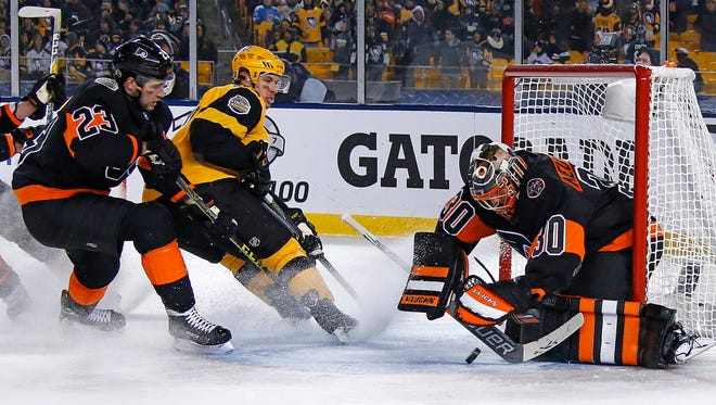 Philadelphia Flyers goalie Michal Neuvirth (30) stops a shot by Pittsburgh Penguins' Sidney Crosby (87) with Brandon Manning (23) defending during the third period of an NHL Stadium Series hockey game at Heinz Field in Pittsburgh.