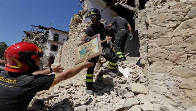 Firefighters retrieve a painting from a church in the small town of Rio, near Amatrice, Italy on Aug. 28, 2016.