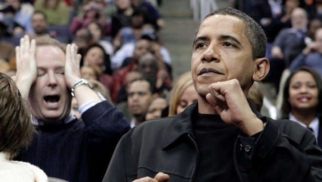 President Barack Obama, right, a Chicago Bulls fan, reacts to a Bulls score while surrounded by Washington Wizards fans during the fourth quarter of their NBA basketball game on Friday, February 27, 2009 in Washington.