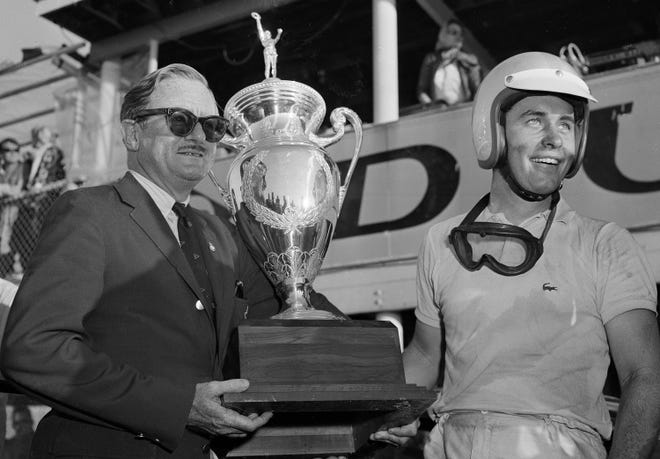 Roger Penske of Gladwyne, Pa., right, receives a trophy from Peter Donald for his record-breaking win in the Nassau, Bahamas tourist Race, Dec. 2, 1962. Penske drove his Ferrari coupe over the 25-lap race at a speed of 88.255 miles per hour, breaking the record set by Sterling Moss in 1960.